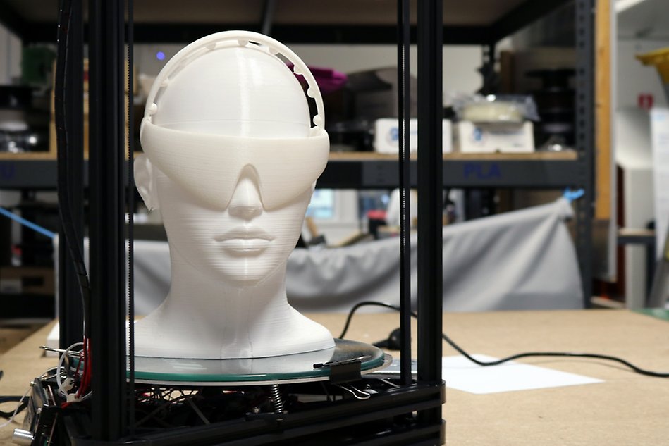 3D-skrivare som skrivet ut ett människohuvud i vit plast. Foto.