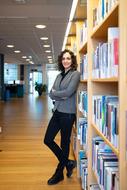 Photo of woman leaning against a book shelf