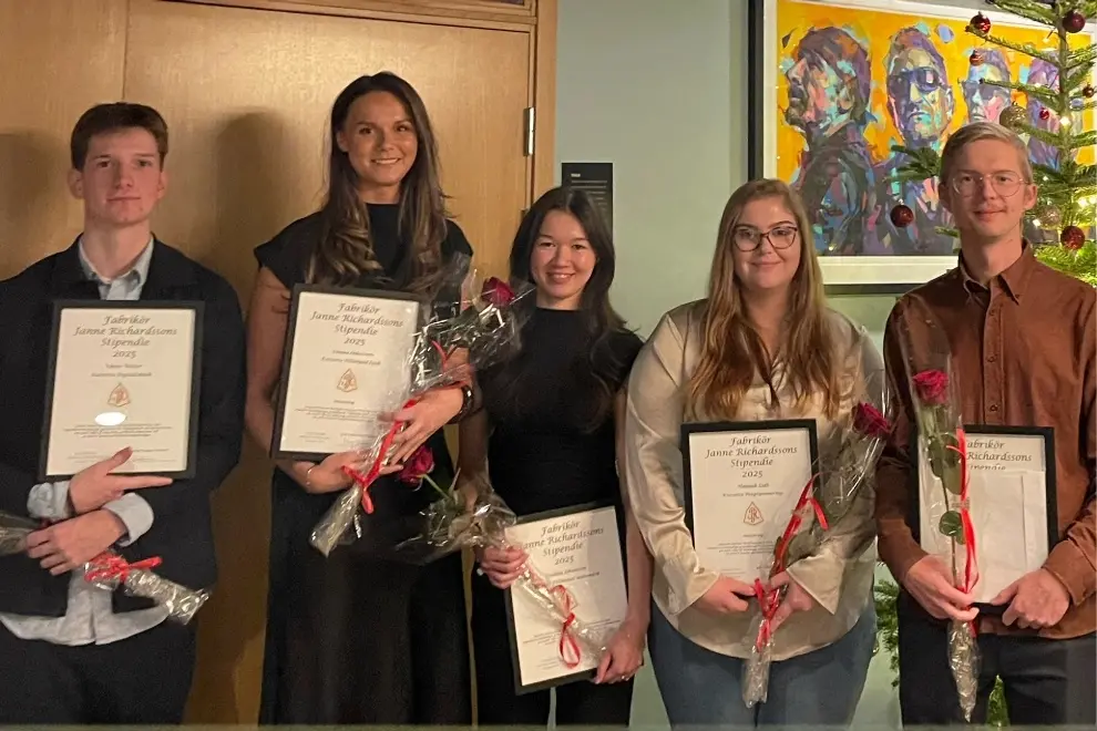 Fem studenter står i rad och ler mot kameran. De håller i en varsin ros och diplom. Foto.