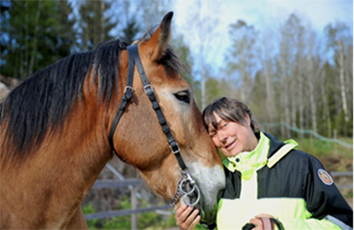 Kvinna kramar sin hästs huvud. Foto.