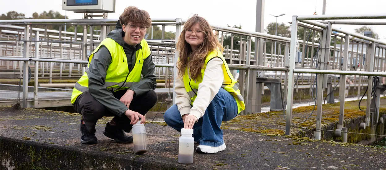 Sex studenter sitter på huk ute de har gula reflexvästar på sig och framför sig har det provflaskor