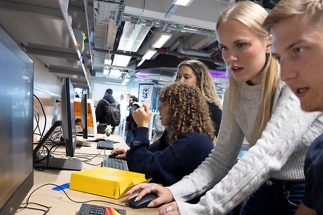 Studenter som sitter på rad ochde närmsta två kollar på en skärm