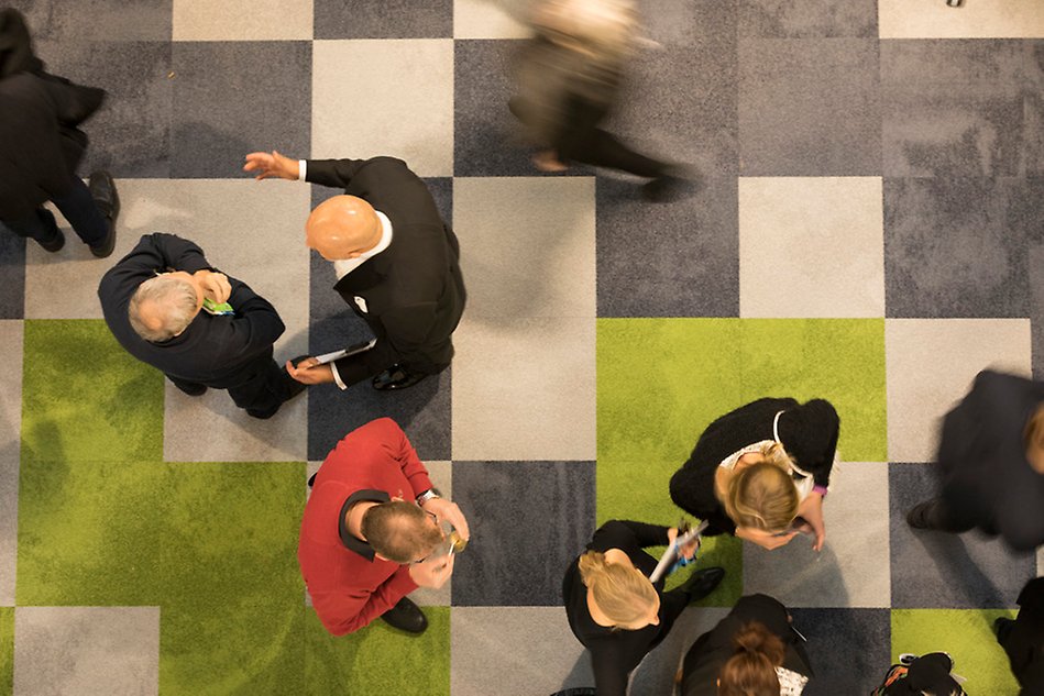 Checkered floor seen from above, people walk on the floor and stand talking. Photo. 