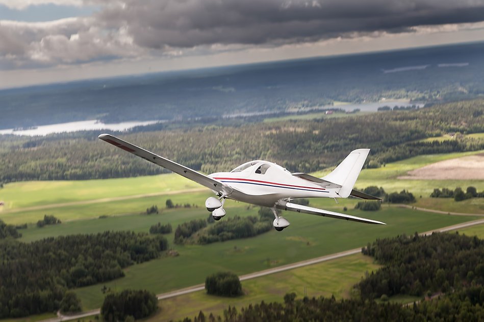 An ultra light plane flying over green fields and forests. Photo.