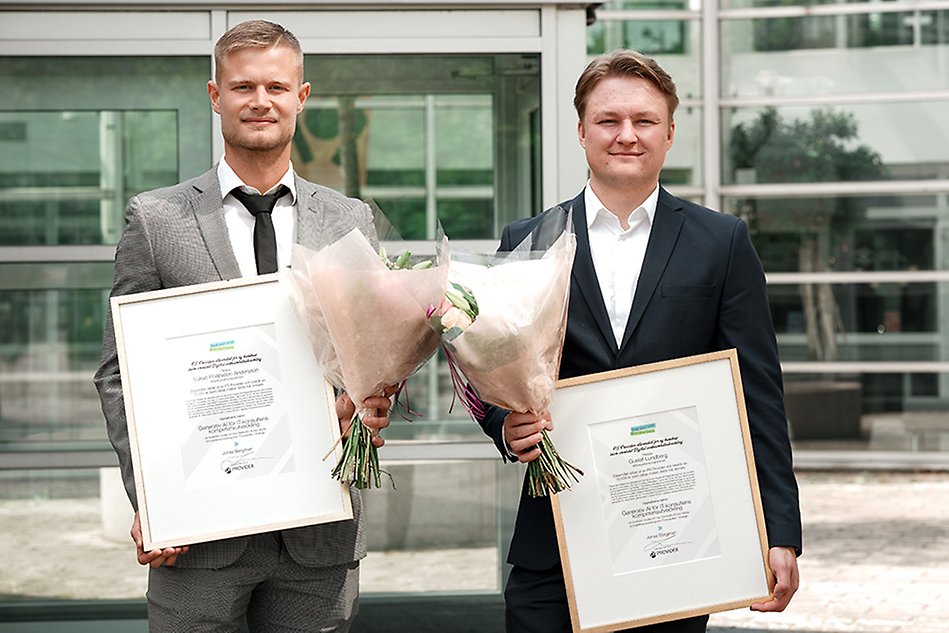 Two people in suits are holding PS Provider scholarship diplomas and flowers. Photo.