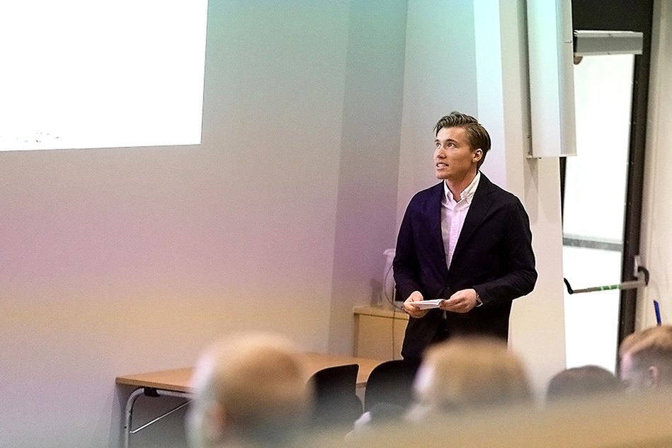 En man står i en föreläsningsal och håller en presentation inför publik.