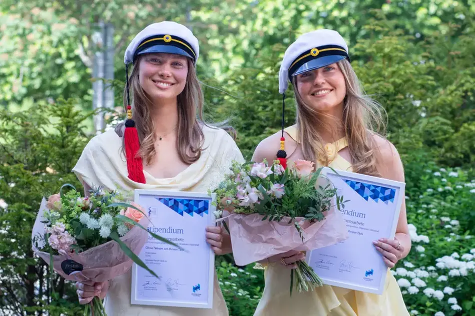 Två personer ler och håller upp sina diplom och statyetter.