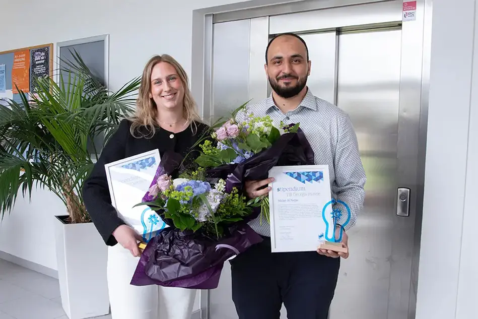 Två unga personer med blommor och diplom.