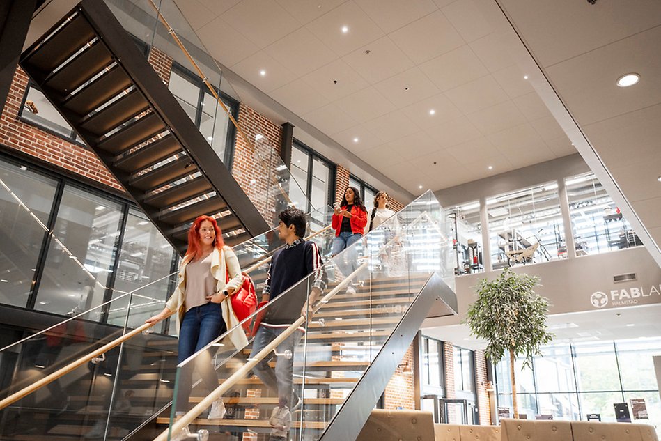 Four young persons walking down the stairs in a bright, modern building. Photo. 