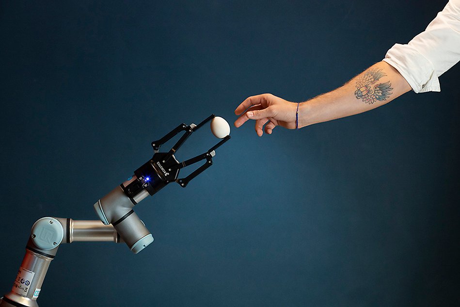 A human arm and a robot arm work together to handle a fragile egg. 