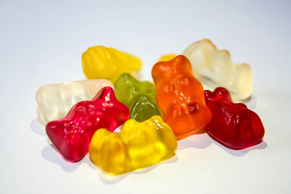 Close-up of different coloured gummy bears on a white background. Photo.