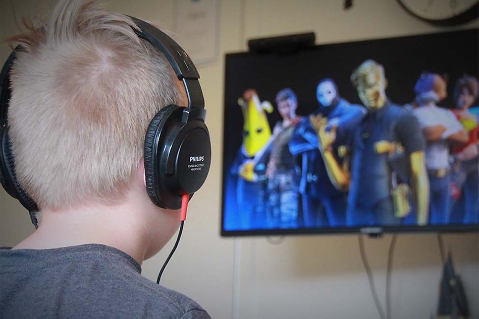 Spel på dataskärm, nacken och bakhuvudet på ett barn med hörlurar