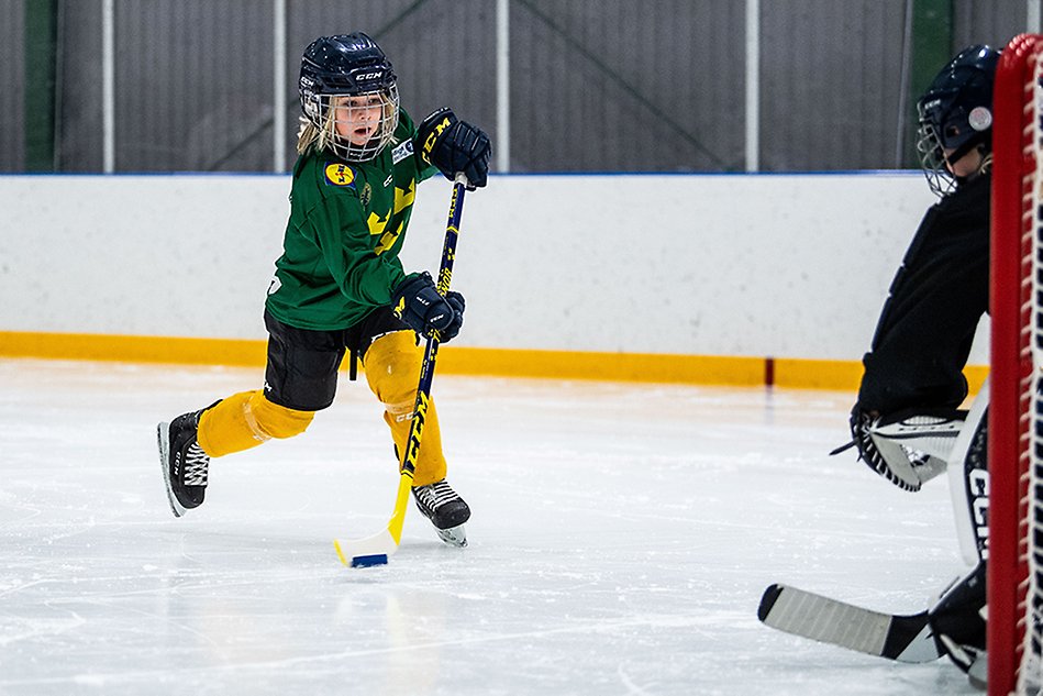 Ett barn i hockeykläder åker mot mål. Foto.