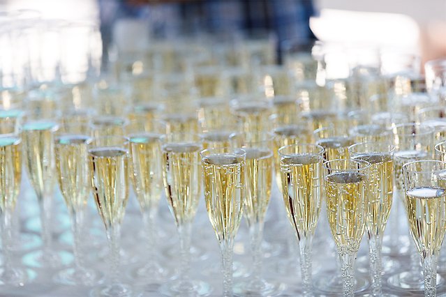 Glasses with sparkling drinks are lined up on a table with a white tablecloth. The glasses are zoomed-in. Photo.