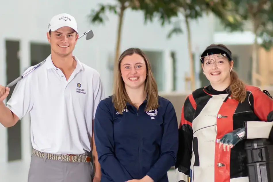 Tre studenter, en golfare, en simmare och en sportskytt, ler mot kameran. Campus i bakgrunden. Foto.