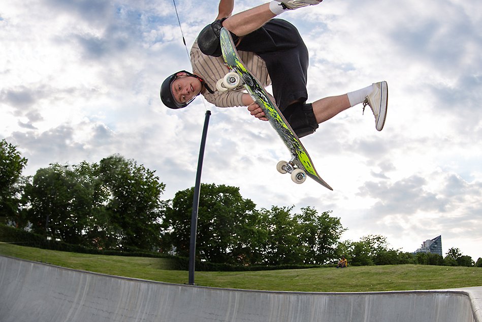 Man är nästan upp och ner i luften med sin skateboard. Foto.