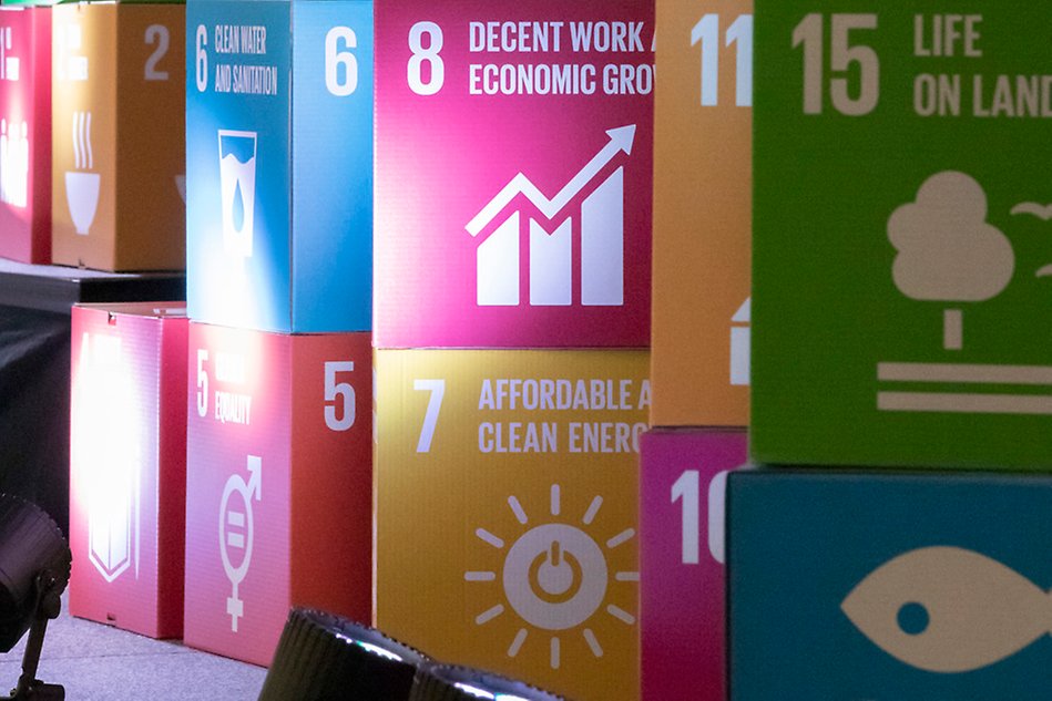 Boxes in carton in different colours, depicting the UN’s goals for sustainable development, are placed on top of each other. Photo.