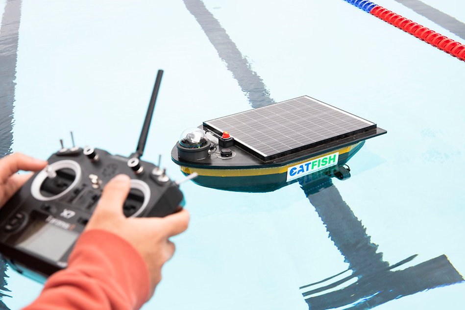 A person uses a remote control to steer the prototype that is in a pool.