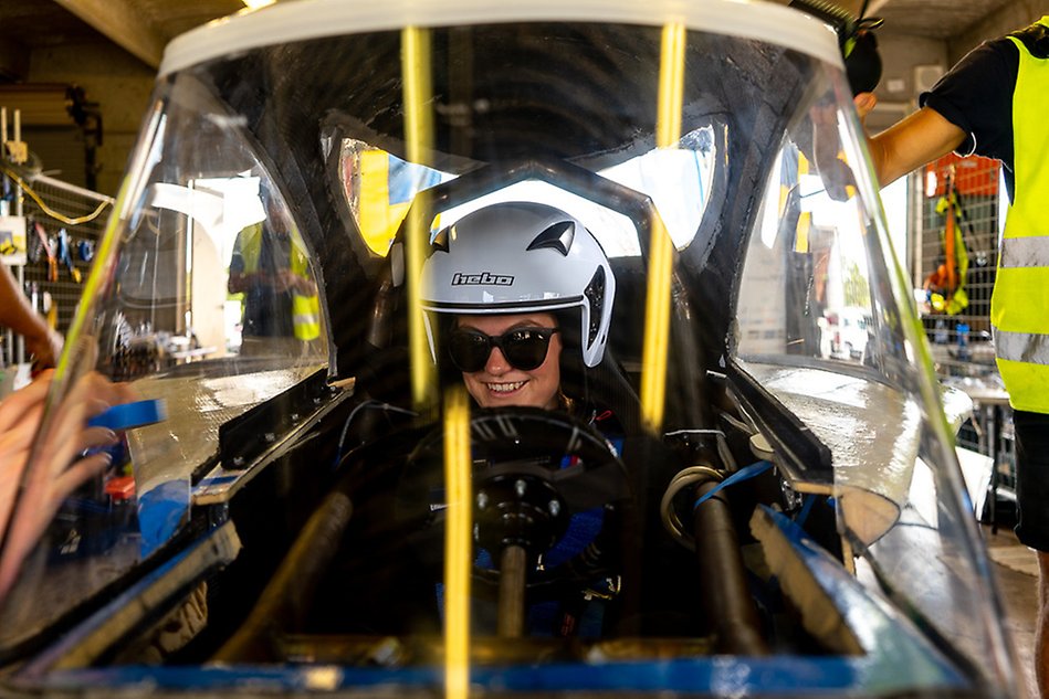 En person som sitter i en racerbil, sedd framifrån. Foto.