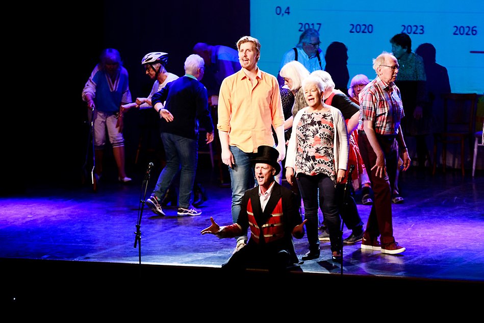 En grupp skådespelare står på en scen och sjunger. 