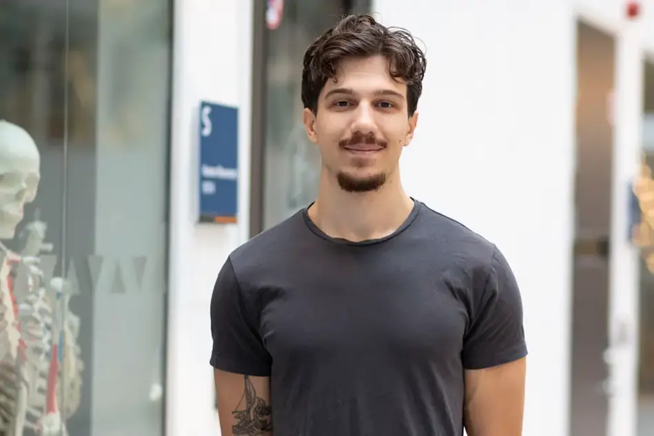 Porträtt på en kvinna som ler. I bakgrunden står en modell av ett skelett. Foto.