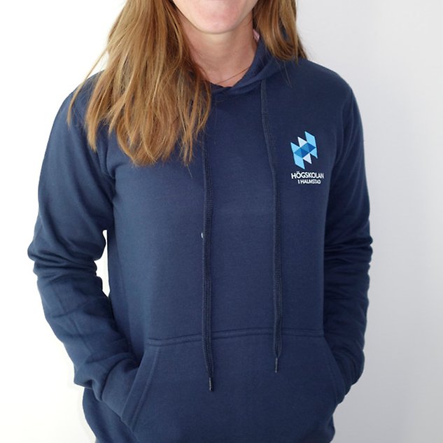 A dark blue long-sleeved shirt with the Högskolan i Halmstad logo is shown on a person whose upper body is visible in the picture. Photo.