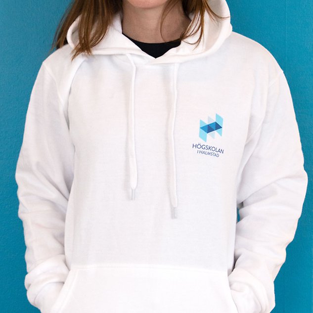 A white long-sleeved shirt with the Högskolan i Halmstad logo is shown on a person whose upper body is visible in the picture. Photo.