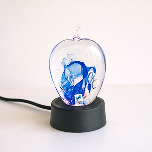 A black lamp base with glass art in blue. Photo.