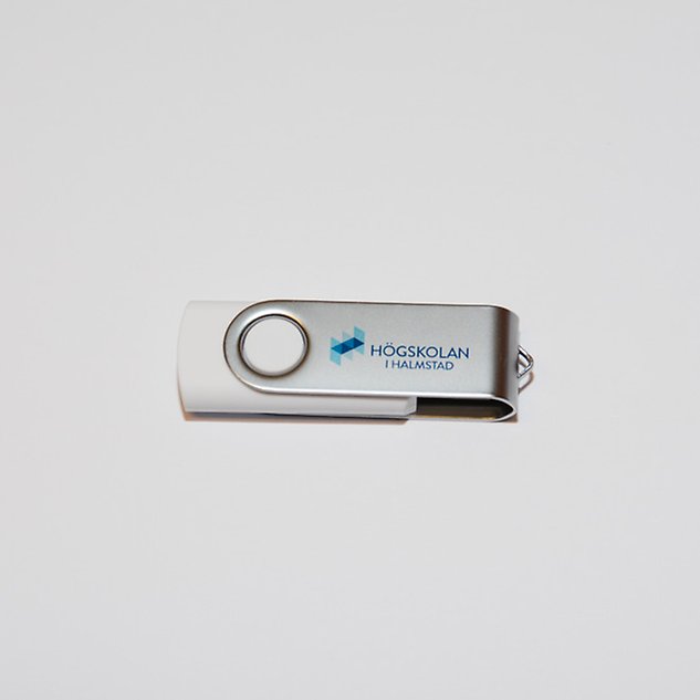 A silver USB stick with the Swedish Halmstad University logo on it. Photo.