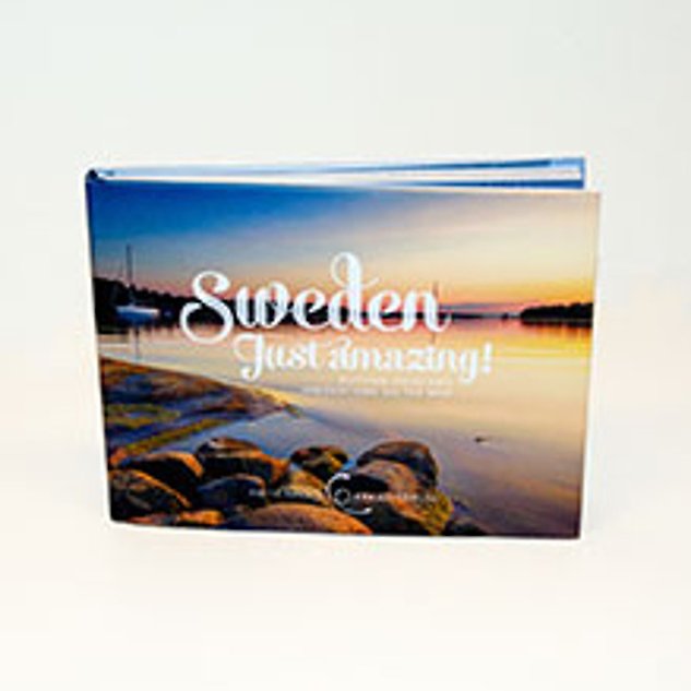 A book with a picture of water and sunset on the cover and the text ”Sweden just amazing”. Photo.