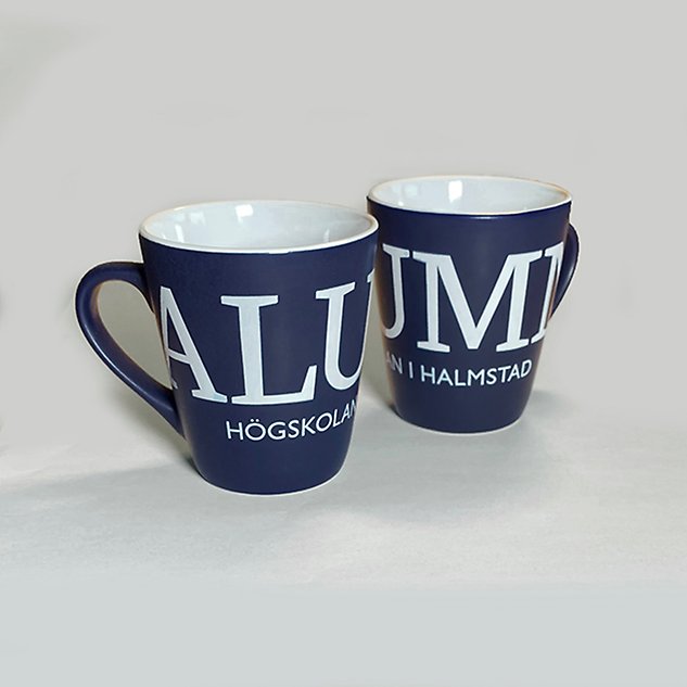 Two mugs in porcelain, with a white inside and a blue outside with the text ”Alumn” in Swedish. Photo.