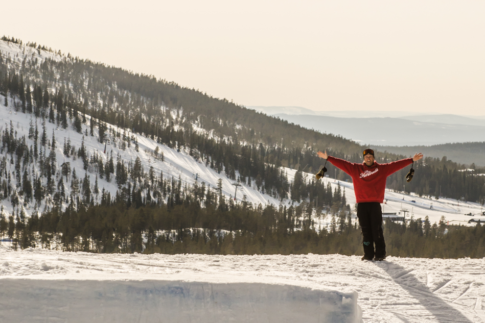 Man står med armarna utåt på ett snöigt berg. Foto.