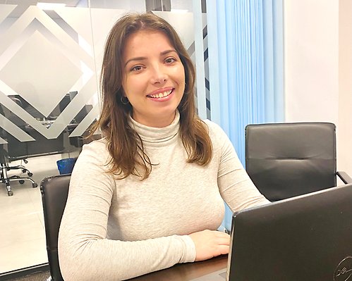 smiling woman at her desk with a computer