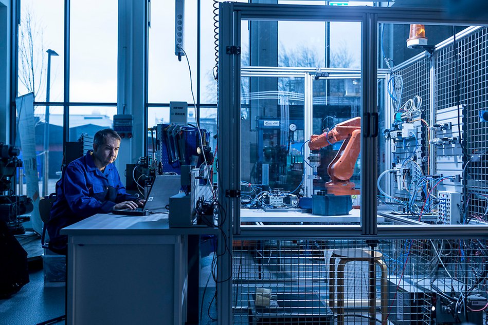 En person sitter i ett mekaniskt laboratorium.