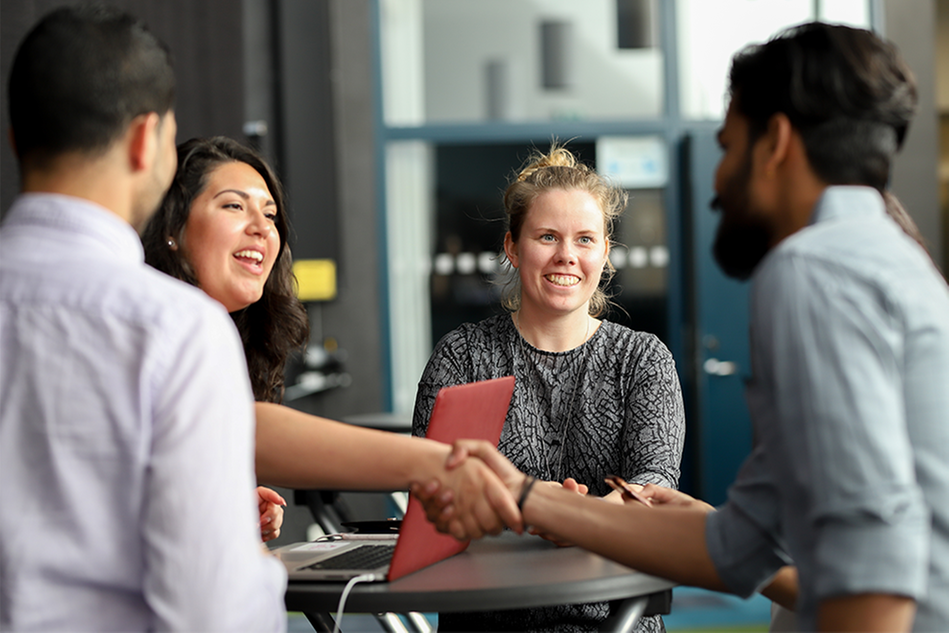 A woman and a man shaking hands, smiling. Photo. 