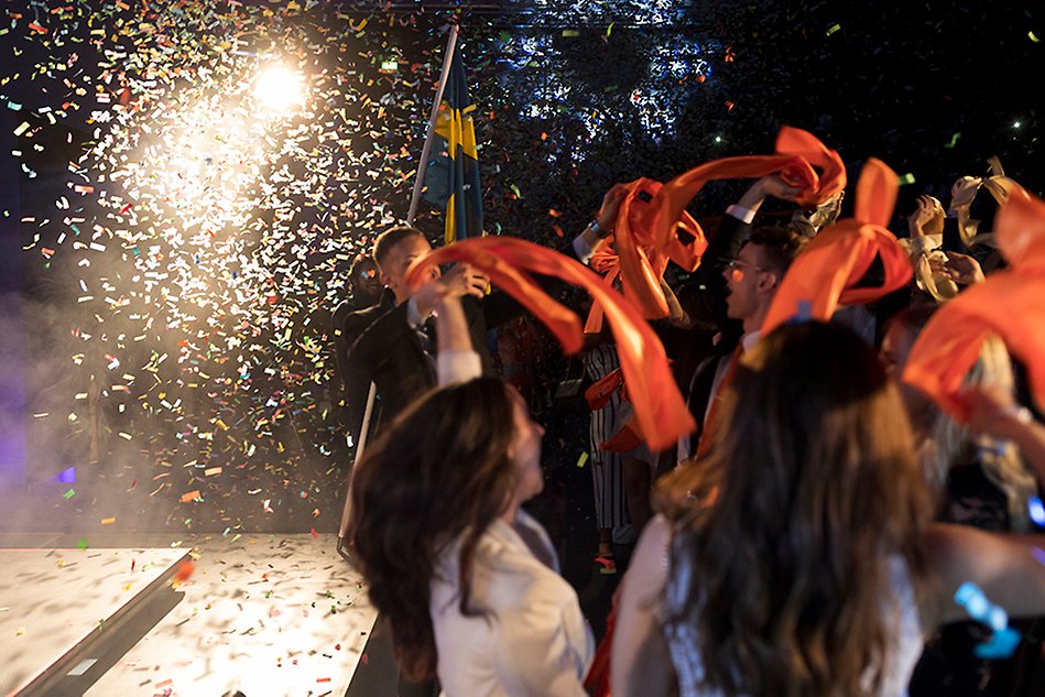 Happy students jumping in a rain of confetti. Photo.